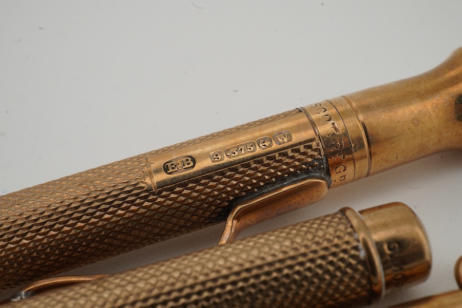 Two engine turned 9ct gold cased pencils including smallest by Sampson Mordan & Co, hallmarked for London, 1937, 7cm, the smaller with engraved inscription, together with a gold plated swizzle stick, larger pencil by E.